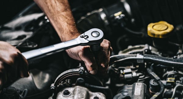 Mechanic using a ratchet wrench to work on a car engine.